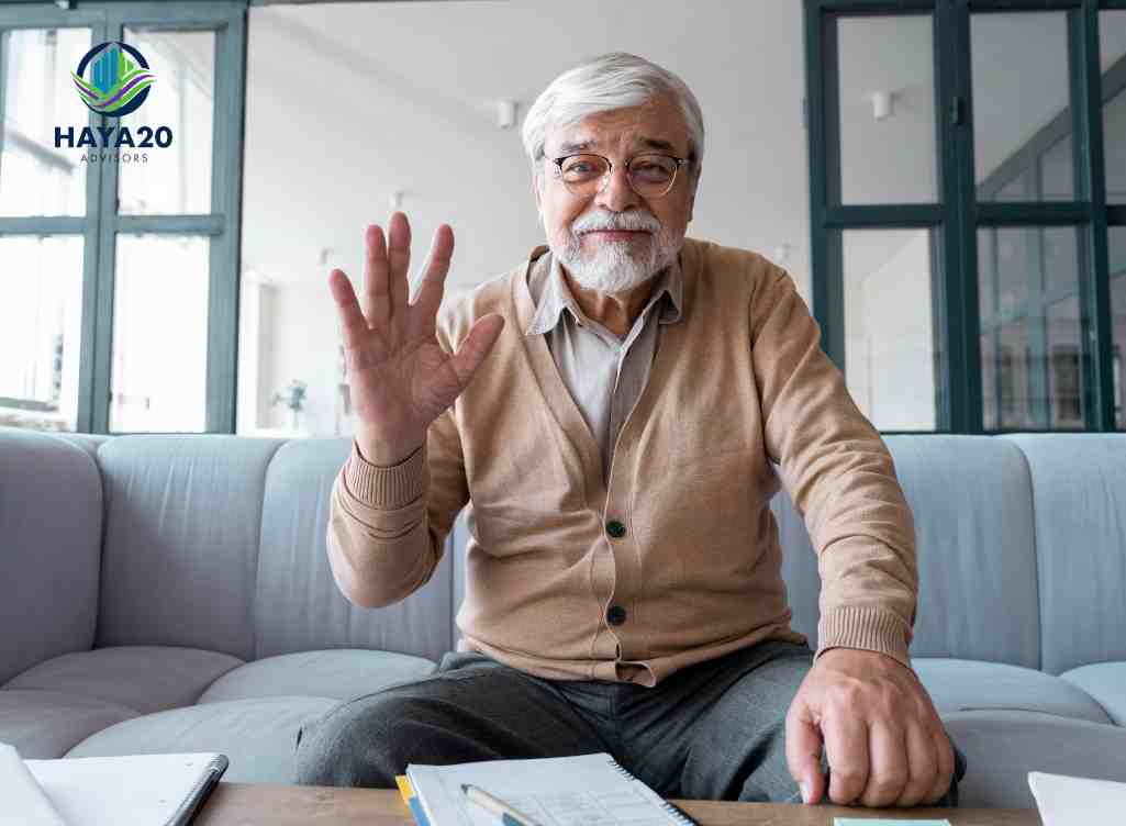 Older man waving during a consultation about life insurance for seniors at home.